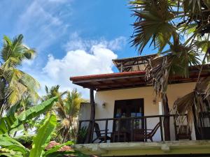 una casa con balcone con palme di Bandulas Beach House a Hikkaduwa