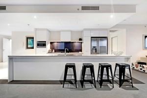 uma cozinha com três bancos de bar e um balcão em Circle on Cavill - Sub Penthouse - Self Contained, Privately Managed em Gold Coast