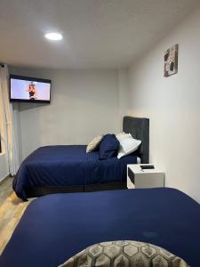 1 dormitorio con 2 camas y TV de pantalla plana en Apartasuites Bogotá 53 cerca al aeropuerto 01, en Bogotá