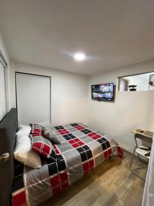 1 dormitorio con 1 cama y TV en la pared en Apartasuites Bogotá 53 cerca al aeropuerto 01, en Bogotá