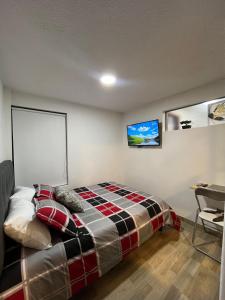 1 dormitorio con 1 cama y TV en la pared en Apartasuites Bogotá 53 cerca al aeropuerto 01, en Bogotá