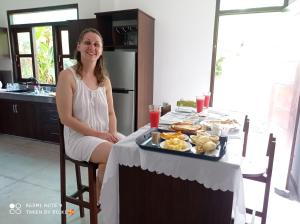 Eine Frau, die an einem Tisch mit einem Tablett Essen sitzt. in der Unterkunft Villa Freiheit Himmel in Bentota