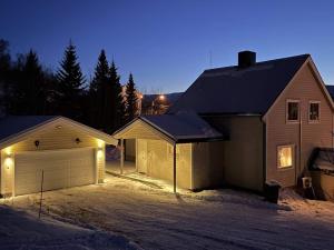 a house with a garage in the snow at night at Holiday home Korsfjorden in Komagfjord