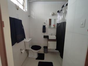 a white bathroom with a toilet and a sink at STUDIO G VISTA ESPETACULAR in Santos