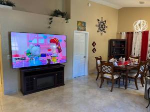 een woonkamer met een tafel en een groot televisiescherm bij Beautiful Modern 3 BR House - Downtown Orlando in Orlando