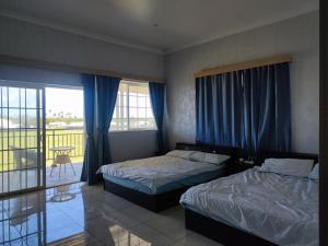 a hotel room with two beds and a balcony at Dupincia Lodge in Nuku‘alofa