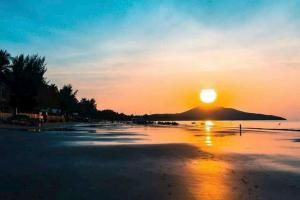 a sunset on a beach with a mountain in the background at Hon Rom Central Beach Resort in Mui Ne