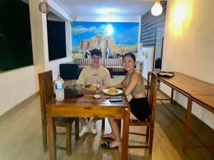 mężczyzna i kobieta siedzący przy stole z jedzeniem w obiekcie Walawa Reach hotel w mieście Udawalawe