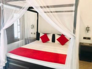 1 dormitorio con cama con dosel y almohadas rojas en Walawa Reach hotel en Udawalawe