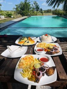 a table topped with plates of food next to a pool at Walawa Reach hotel in Udawalawe