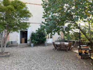 a patio with a table and chairs and a grill at Grande maison familiale, 5 chambres, jardin, proche 24 Heures du Mans et abbaye de Solesmes. - FR-1-410-427 in Juigné-sur-Sarthe