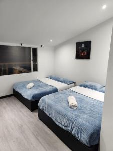 Habitación con 3 camas y edredones azules. en Casa Chimenea a 5 minutos del Aeropuerto, en Bogotá