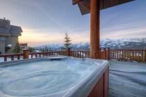 a hot tub on a deck with mountains in the background at 5 Bandit Way by Moonlight Basin Lodging in Big Sky