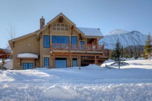 a log home with a deck in the snow at 5 Bandit Way by Moonlight Basin Lodging in Big Sky