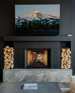 a living room with a fireplace with a tv above it at 7 Speedwell Drive by Moonlight Basin Lodging in Big Sky