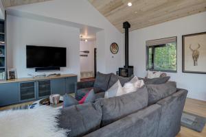 a living room with a gray couch and a flat screen tv at 17 Lake Cabin by Moonlight Basin Lodging in Big Sky