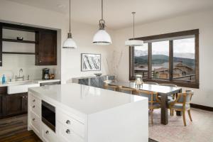 a kitchen with a white island and a dining table at 4B Lodgeside by Moonlight Basin Lodging in Big Sky