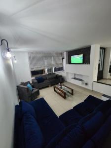 sala de estar con sofá azul y TV en Casa Chimenea a 5 minutos del Aeropuerto, en Bogotá