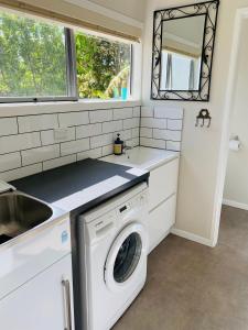 a kitchen with a washing machine and a sink at Mission Retreat in Kerikeri