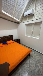 a bedroom with an orange bed and a air conditioner at LE NID d'oiseau studio meublé climatisé chez l'habitant in Deshaies