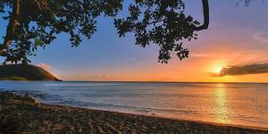 a sunset on the beach with the sun setting over the water at LE NID d'oiseau studio meublé climatisé chez l'habitant in Deshaies