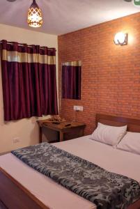 a bedroom with a bed and a red brick wall at Cloudsmisty kodai in Kodaikānāl