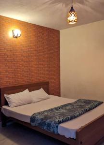 a bed in a room with a brick wall at Cloudsmisty kodai in Kodaikānāl