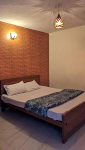 a bed in a room with a brick wall at Cloudsmisty kodai in Kodaikānāl