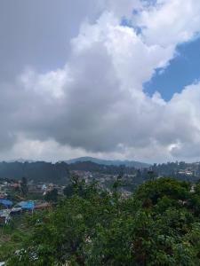 Blick auf eine Stadt mit wolkigem Himmel und Bäumen in der Unterkunft Cloudsmisty kodai in Kodaikanal