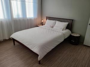 1 dormitorio con 1 cama grande con sábanas y almohadas blancas en City Central & Cosy House en Gwangju