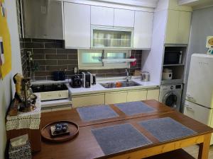 a kitchen with white cabinets and a wooden table at City Central & Cosy House in Gwangju
