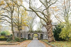 an old building with an archway in a park with trees at Central & Lovely Apartment in Hannover in Hannover