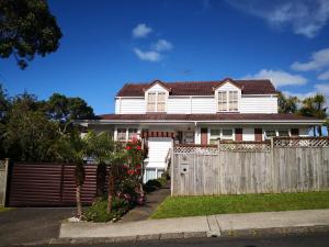 een wit huis met een houten hek bij Rose Room in Auckland