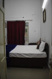 アラハバードにあるBAGEECHA VILLAの赤いカーテンが付いた部屋のベッド1台