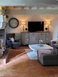 ein Wohnzimmer mit einem TV, einem Sofa und einem Tisch in der Unterkunft Gîte de charme, bord de Loire Ma Maison Angevine in Le Thoureil