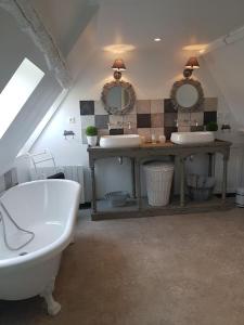 ein Badezimmer mit zwei Waschbecken, einer Badewanne und zwei Spiegeln in der Unterkunft Gîte de charme, bord de Loire Ma Maison Angevine in Le Thoureil