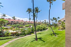 a lawn with palm trees in front of a resort at Cozy Condo in Kihei at Kamaole Sands Building 3 Unit 202 in Wailea