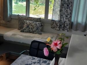 a room with a window seat with a table and flowers at Village Homestay in Udon Thani