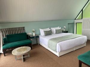 a bedroom with a bed and a green chair at Hummingbird St.Clare Villas in Dimbula