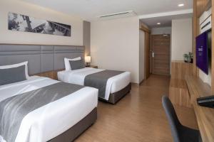 ラートクラバンにあるCanalis Suvarnabhumi Airport Hotelのベッド2台と机があるホテルの部屋