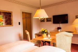 a room with a table and a bed and a television at Garden-Hotel Reinhart in Prien am Chiemsee