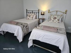 Duas camas com lençóis brancos e almofadas num quarto em The Witch's Inn em Philippolis