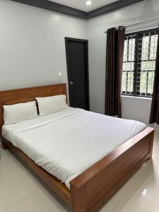 a bedroom with a large bed with white sheets at Kosher Livings in Kalpetta