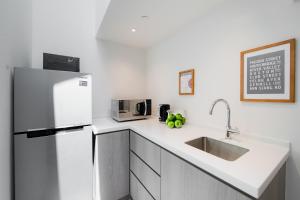 a white kitchen with a refrigerator and a sink at Heritage Collection on Chinatown - A Digital Hotel in Singapore