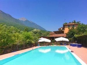 a large swimming pool with a house and mountains in the background at Locanda del Ponte B&B in Balsorano Vecchio