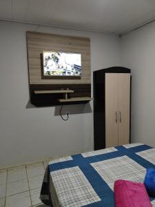 a bedroom with a bed and a tv on the wall at Casa inteira in Solânea