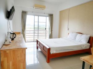een slaapkamer met een bed, een televisie en een balkon bij Fang Villa Hotel in Fang