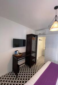 um quarto com uma cama, uma secretária e uma televisão em Fides Boutique Hotel em Luang Prabang