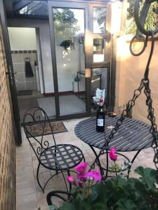 a table with a bottle of wine and pink flowers at Kyasaja Home away from home in Pretoria