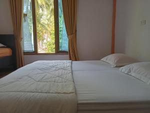 een slaapkamer met een groot wit bed en een raam bij Walur Surf Villa in Krui